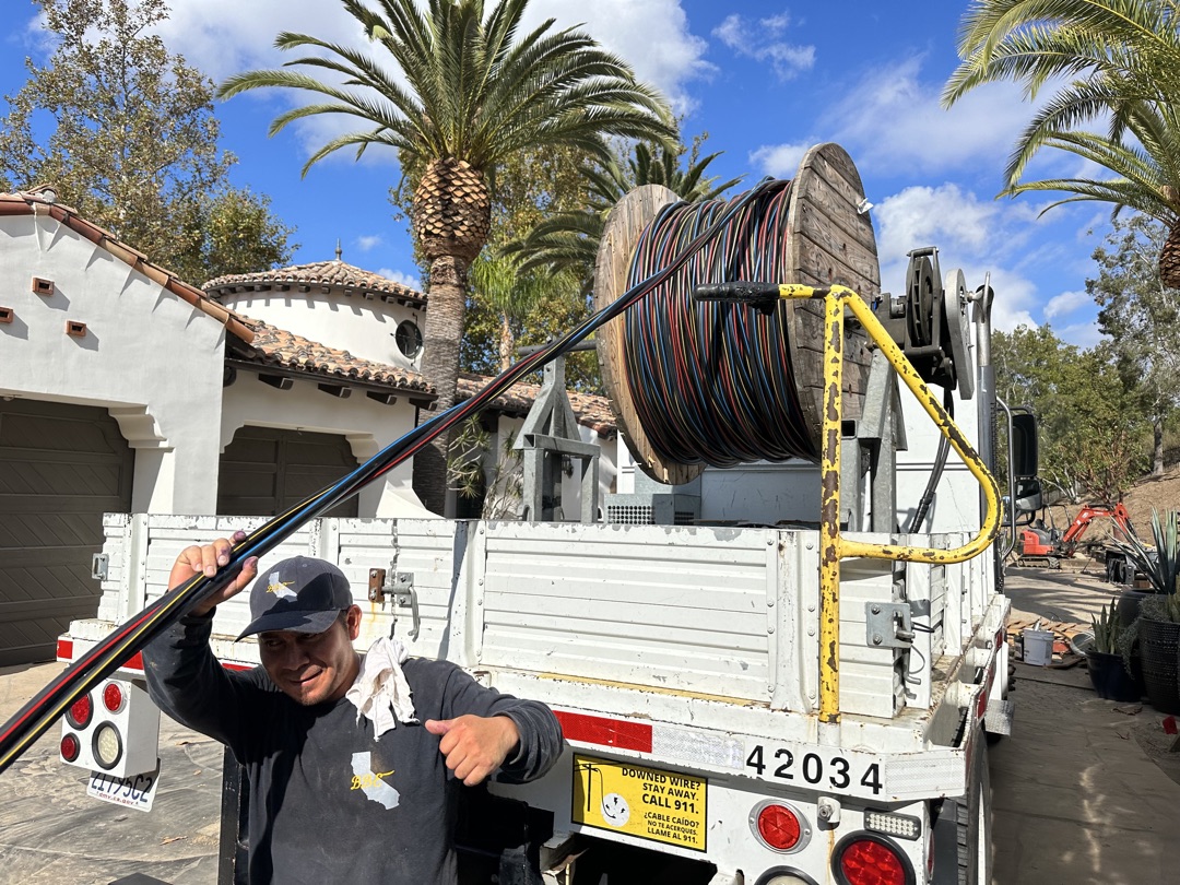 BBE electrician with large cable reel on utility truck at a luxury Spanish-style estate in Los Angeles